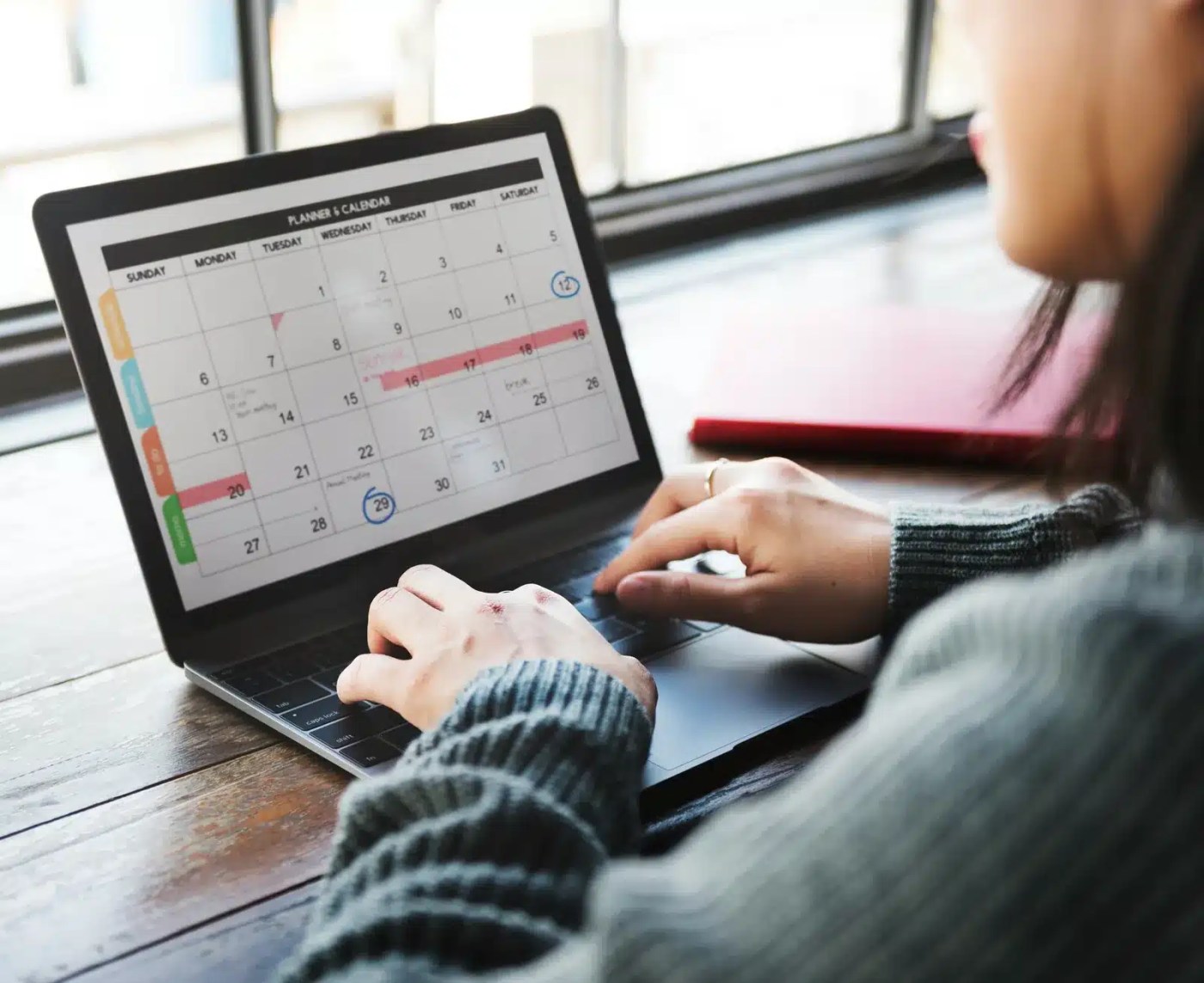 Gestionnaire qui consulte un calendrier mensuel sur un portable pour planifier les quarts de son équipe