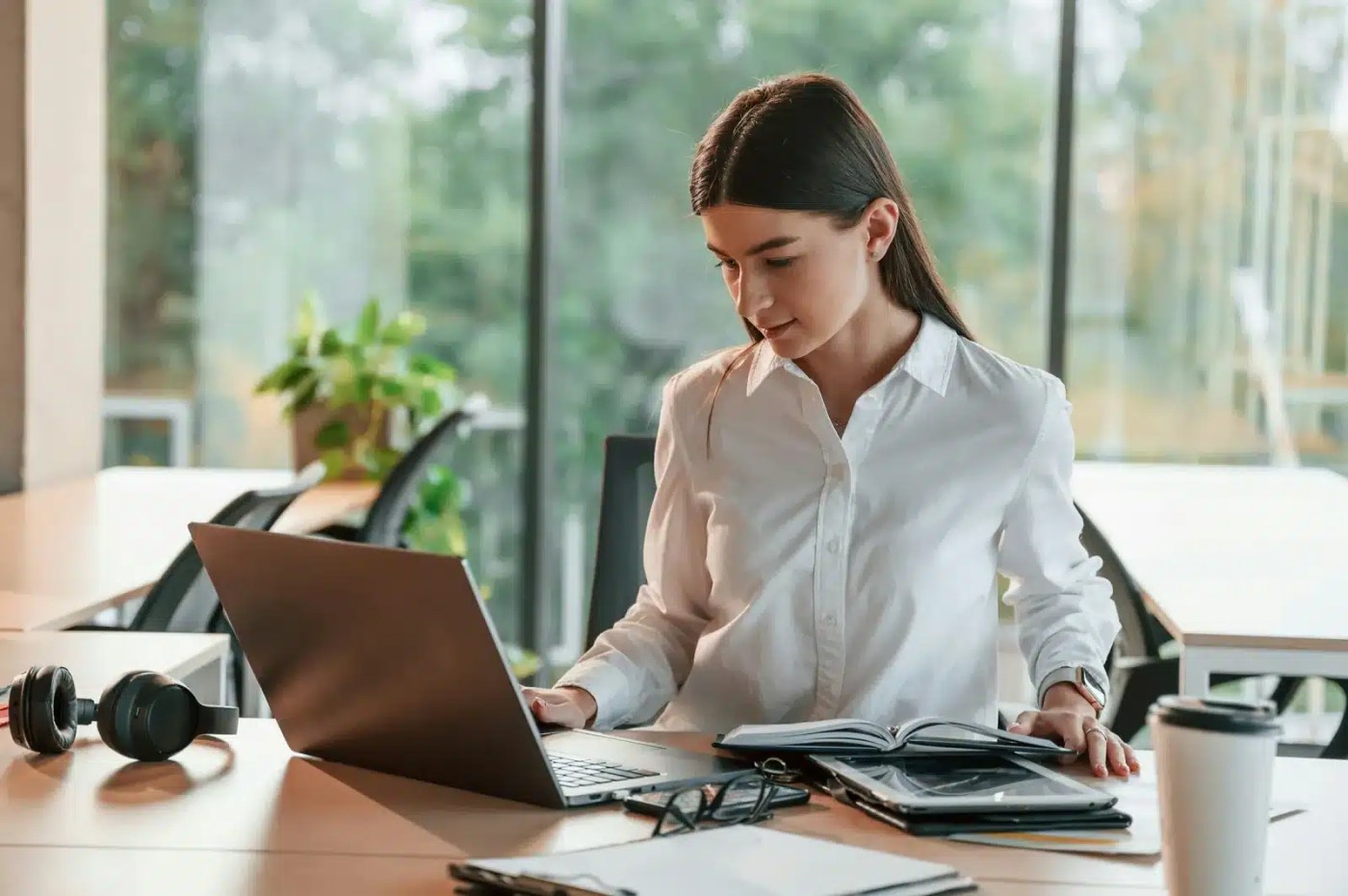 Employée de retour au bureau après un congé parental, qui reprend ses dossiers entre portable et agenda