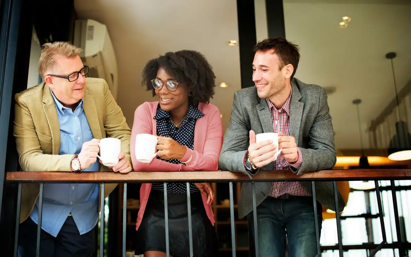 Three colleagues chatting over coffee during a break, a moment governed by work hours and break rules in Canada
